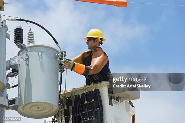 caucasian worker in cherry picker repairing power line - onderhoudsingenieur stockfoto's en -beelden