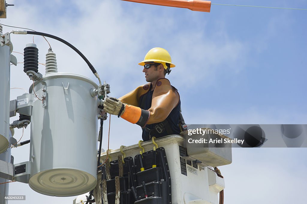 Caucasian worker in cherry picker repairing power line