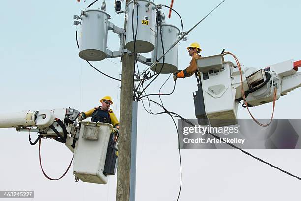 caucasian workers in cherry pickers repairing power line - telephone pole stock pictures, royalty-free photos & images