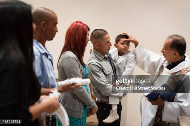 priest anointing boy in church - mom blessing son stockfoto's en -beelden