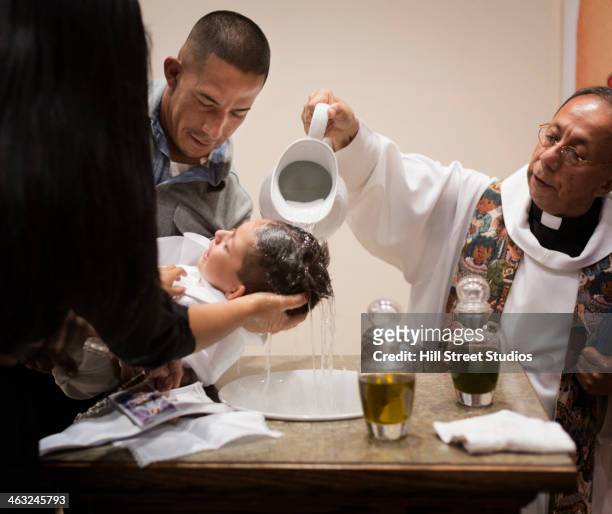 priest baptizing boy in church - catholic baptism stock-fotos und bilder