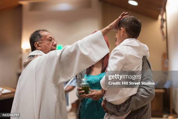 priest anointing boy in church - catholic baptism stock-fotos und bilder