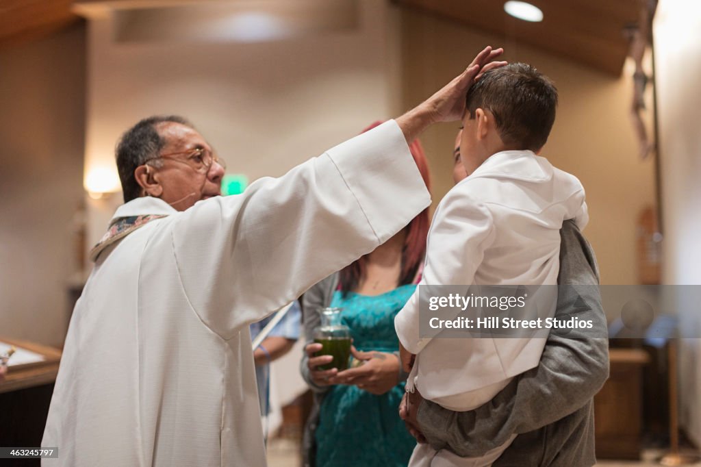 Priest anointing boy in church