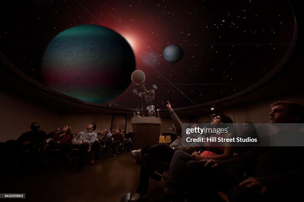 Students watching planets in planetarium