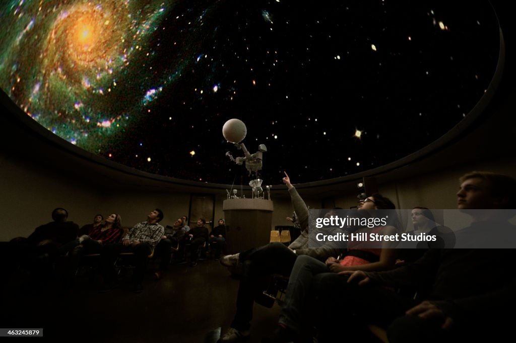 Students watching galaxy in planetarium