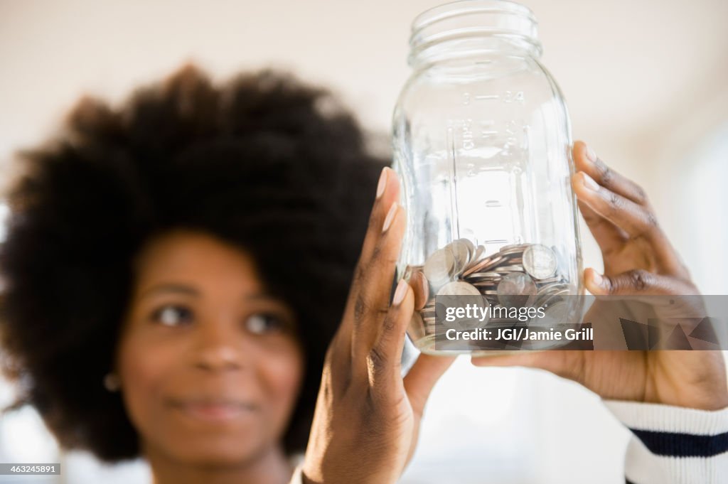 Mixed race woman holding jar of change