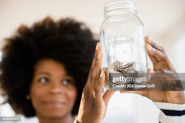 mixed race woman holding jar of change - nest egg stock pictures, royalty-free photos & images