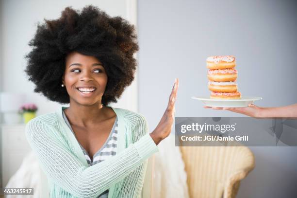 mixed race woman refusing donuts - verweigern stock-fotos und bilder