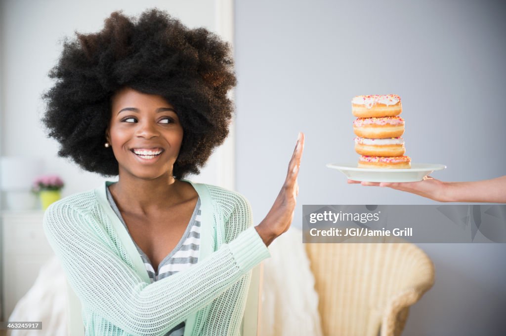 Mixed race woman refusing donuts