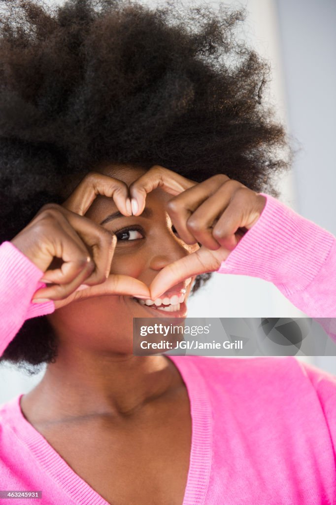 Mixed race woman making heart-shape with fingers