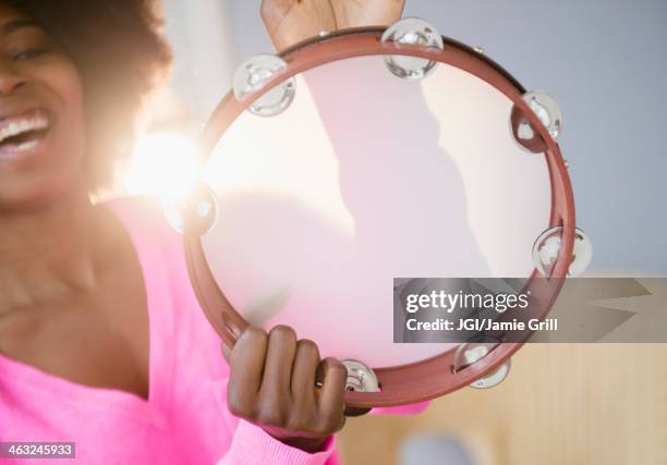 mixed race woman playing tambourine - tambourine stock pictures, royalty-free photos & images