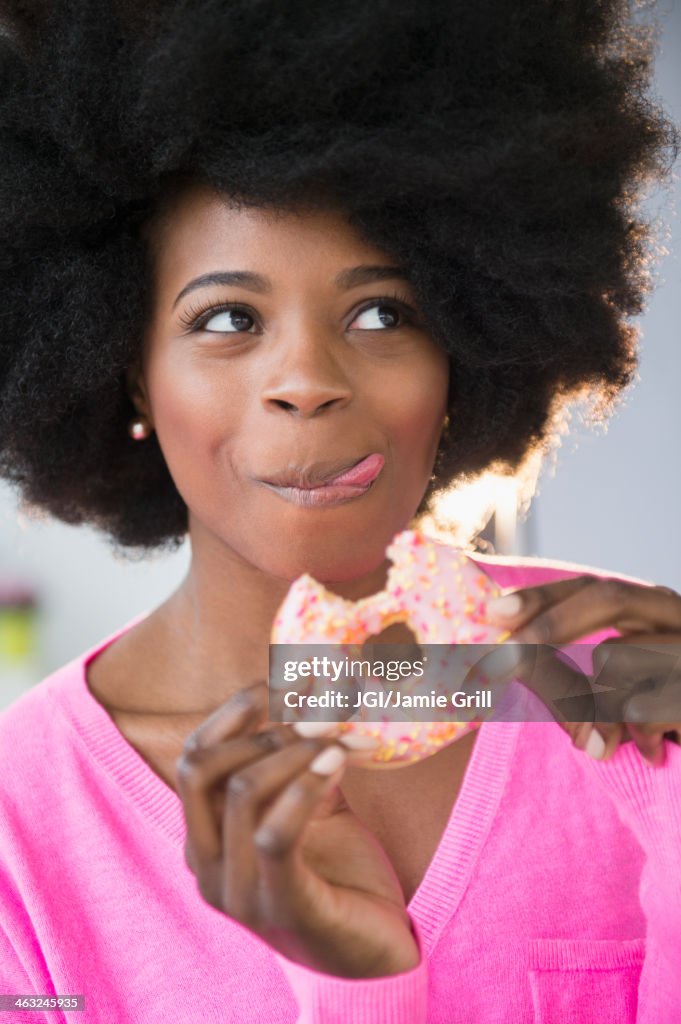 Mixed race woman eating donut