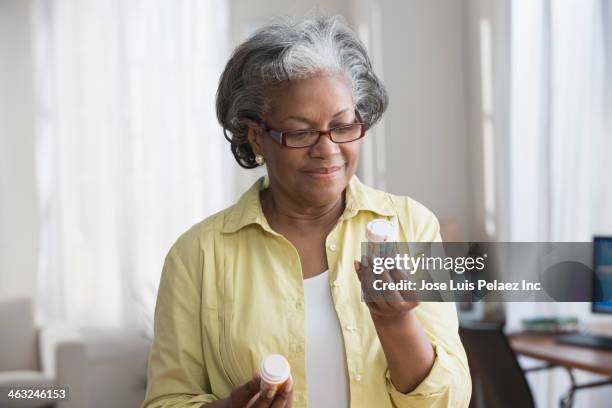 black woman reading prescription bottles - comprimés en flacon photos et images de collection