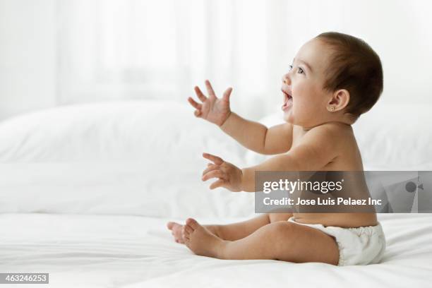 hispanic baby sitting on bed - baby reaching stock pictures, royalty-free photos & images