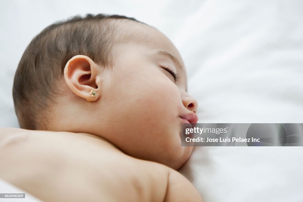 Hispanic baby sleeping on bed