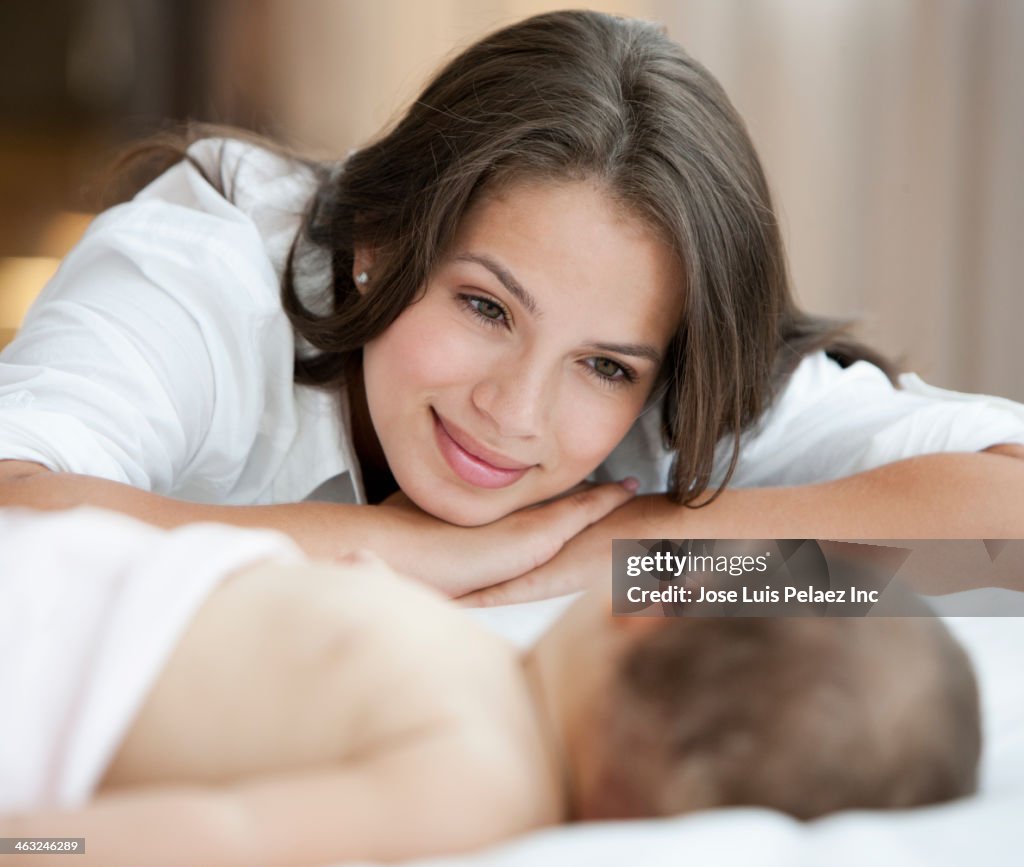 Hispanic mother admiring sleeping baby
