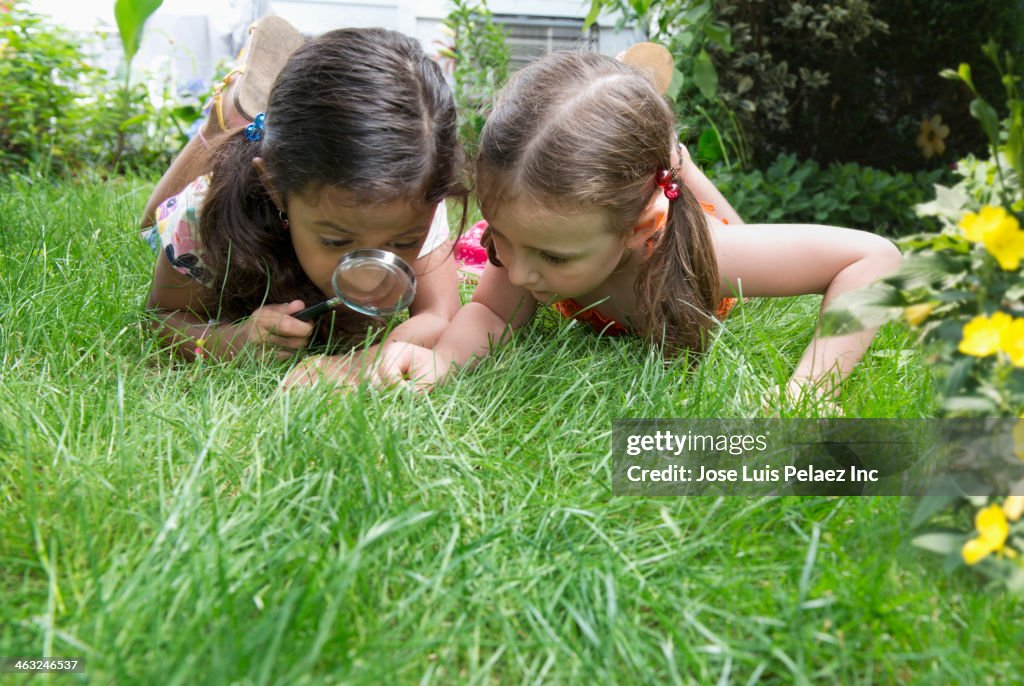 Girls using magnifying glass in grass