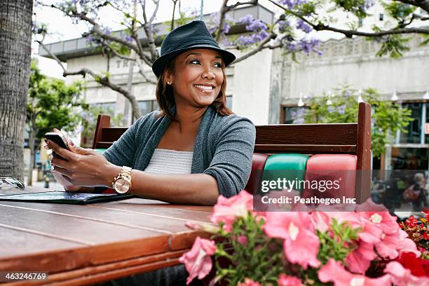 black woman using cell phone at sidewalk cafe - african american restaurant texting stockfoto's en -beelden