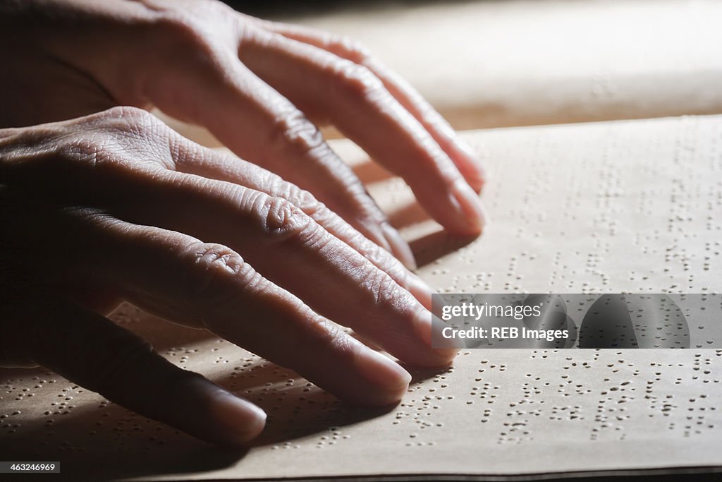 Close up of Hispanic person reading Braille
