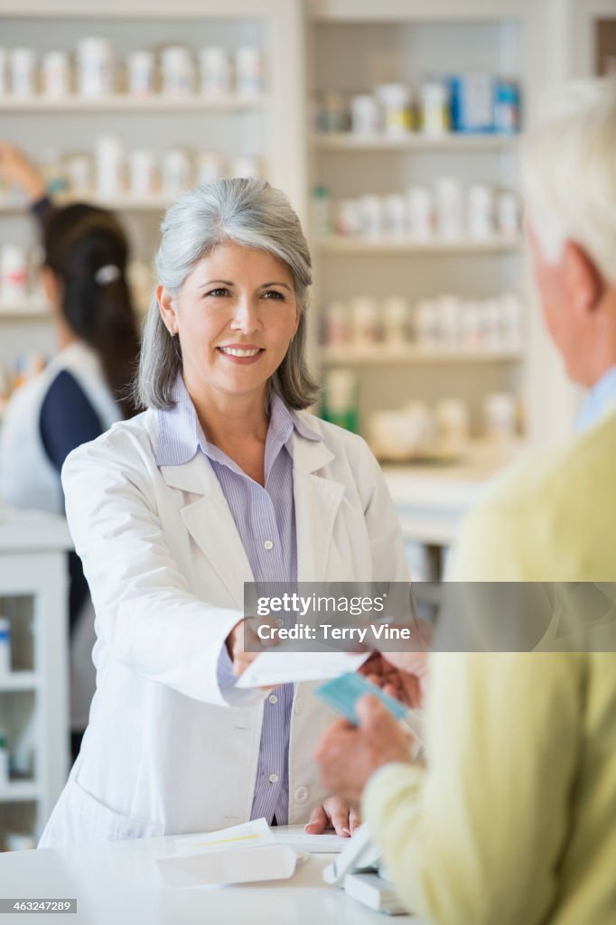 Pharmacist giving prescription to customer