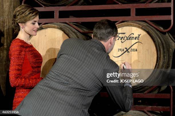 Spanish King Felipe autographs a barrel of cava beside his wife Queen Letizia during their visit to Freixenet winery in the north-eastern Spanish...