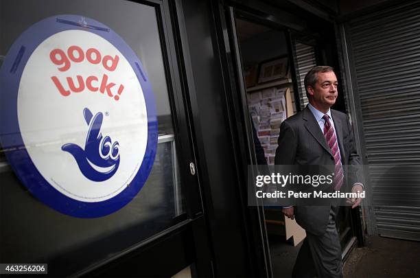 United Kingdom Indepedence Party leader Nigel Farage walks past a National Lottery sign as he exits a shop during campaigning on February 12, 2015 in...