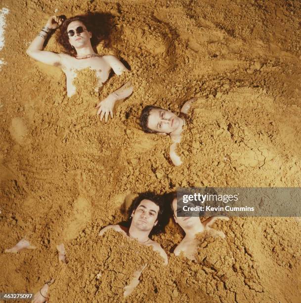 Gothic rock band The Mission buried in sand, circa 1990.