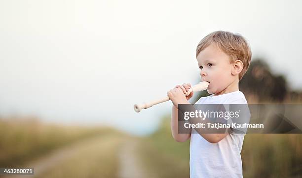 young boy playing recorder outside in summer - blockflöte stock-fotos und bilder