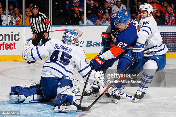 Anders Lee of the New York Islanders under pressure from Roman Polak of the Toronto Maple Leafs scores a first period goal past Jonathan Bernier of...