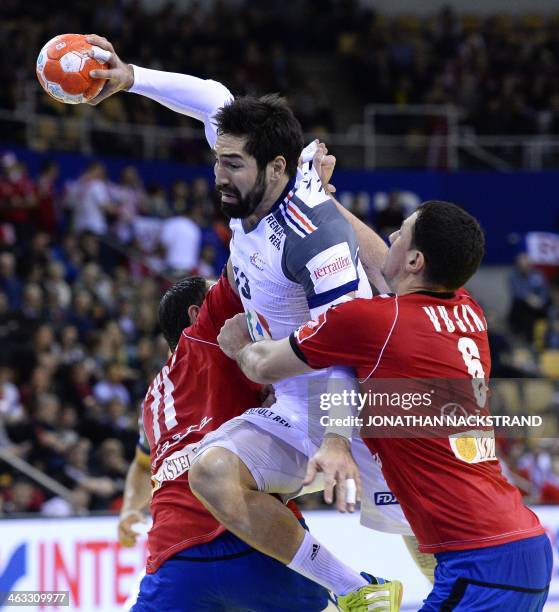 France's centre back Nikola Karabatic jumps to score on Serbia's right back Marko Vujin and pivot Alem Toskic during the men's EHF Euro 2014 Handball...
