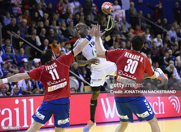 France's right wing Luc Abalo jumps to score on Serbia's pivot Alem Toskic and left back Drasko Nenadic during the men's EHF Euro 2014 Handball...
