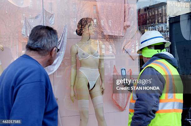 Construction worker takes a cell phone photograph of a mannequin with pubic hair in the window of an American Apparel shop on Houston Street in the...