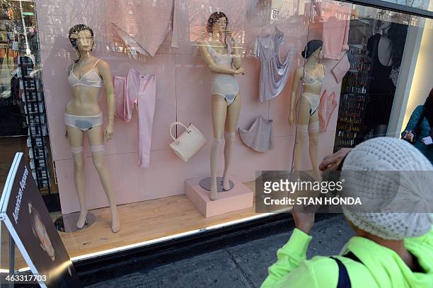Woman takes a cell phone photograph of mannequins with pubic hair in the window of an American Apparel shop on Houston Street in the Soho section of...