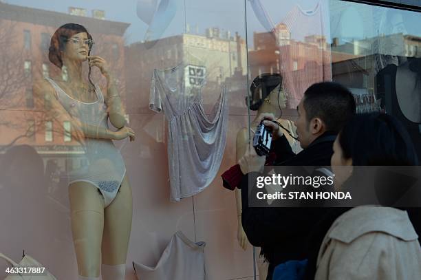 Couple look at a mannequin with pubic hair in the window of an American Apparel shop on Houston Street in the Soho section of Manhattan January 17,...