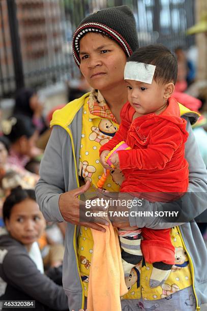 Cambodian mother stands as she carries her child in front of Kantha Bopha hospital in Phnom Penh, February 13, 2015. AFP PHOTO / TANG CHHIN SOTHY
