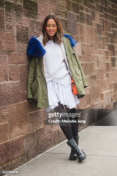 Blogger Aimee Song of Song of Style wears a Marissa Webb sweater and dress shirt, Chloe clutch, and Hunter boots at Streets of Manhattan on February...