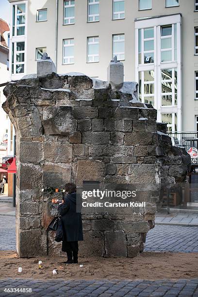 Woman lights a candle on an original part of the Frauenkirche before the commemoration of the 70th anniversary of the Allied firebombing of Dresden...