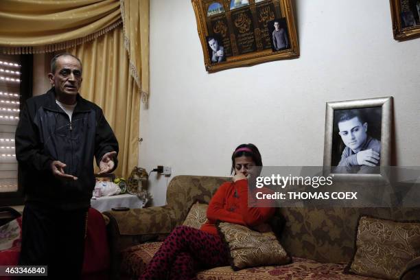 The father of Arab-Israeli Muhammad Said Ismail Musallam gestures as his mother sits next to a framed portrait of their son, who is captured by the...