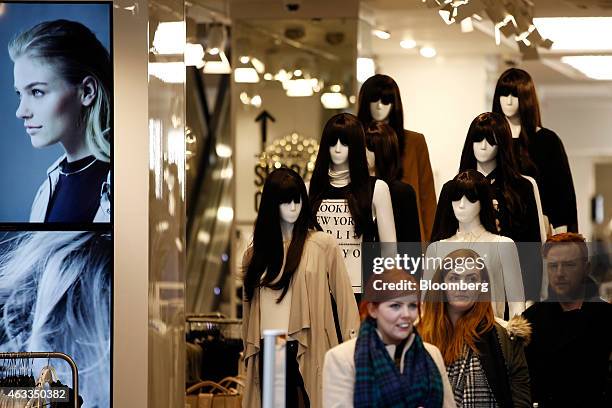 Customers pass mannequins displaying women's clothes as they exit a New Look fashion store, operated by New Look Group Ltd., on Oxford Street in...