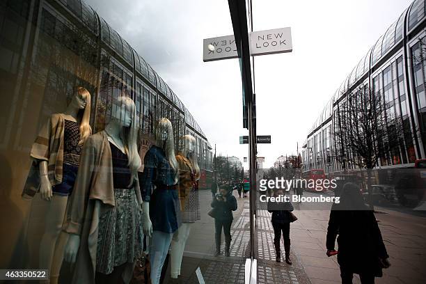 Pedestrians walk past mannequins displaying clothes in the window of a New Look fashion store, operated by New Look Group Ltd., on Oxford Street in...