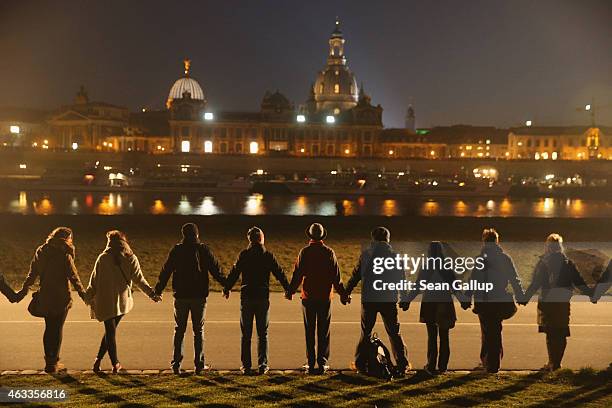 People standing along the Elbe River across from the historic Dresden city center link hands to create a human chain in commemoration of the 70th...