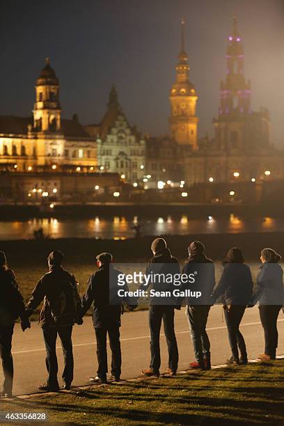 People standing along the Elbe River across from the historic Dresden city center link hands to create a human chain in commemoration of the 70th...