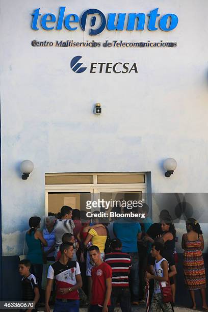 Pedestrians pass by people waiting in line at an Empresa de Telecomunicaciones de Cuba SA office, the state-run telecom company, in Santiago de Cuba,...
