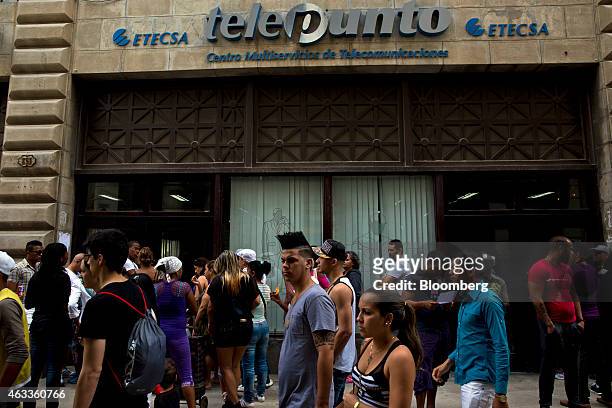 Pedestrians pass by people waiting in line at an Empresa de Telecomunicaciones de Cuba SA office, the state-run telecom company, in Havana, Cuba, on...