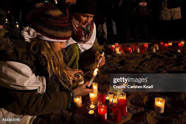 Two women light candles in front of the Frauenkirche to commemorate the 70th anniversary of the Allied firebombing of Dresden on February 13, 2015 in...