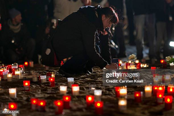 Woman lights a candle in front of the Frauenkirche to commemorate the 70th anniversary of the Allied firebombing of Dresden on February 13, 2015 in...