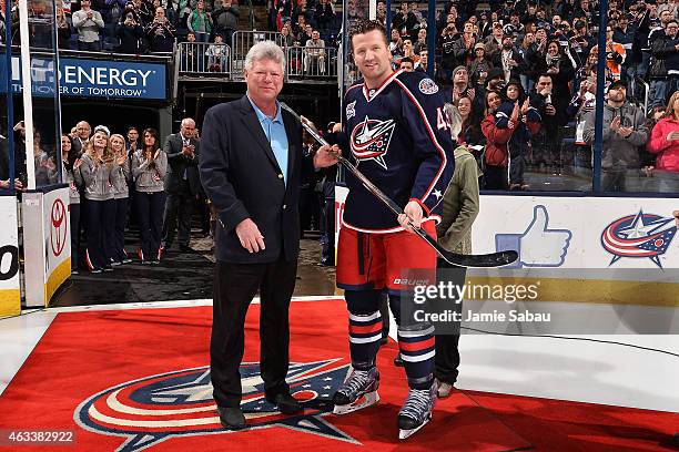 John P. McConnell, majority owner of the Columbus Blue Jackets, presents a silver stick to Scott Hartnell in recognition for playing 1,000 games in...