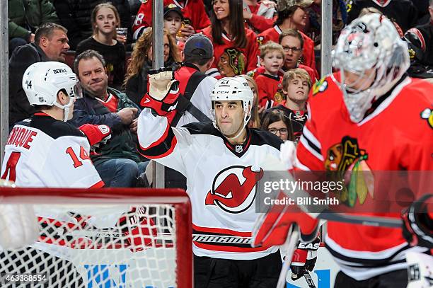 Scott Gomez and Adam Henrique of the New Jersey Devils celebrate behind goalie Corey Crawford of the Chicago Blackhawks after the Devils scored in...