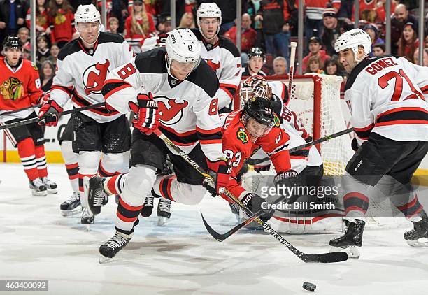 Dainius Zubrus of the New Jersey Devils and Kris Versteeg of the Chicago Blackhawks lunge for the puck during the NHL game at the United Center on...