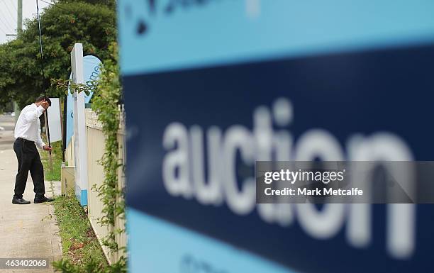 An estate agent puts up signs before the home auction for a four-bedroom house at 230 Blacktown Road on February 14, 2015 in Blacktown, Australia....